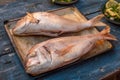 High-angle shot of two Ã¢â¬â¹Ã¢â¬â¹breams with cut stomachs on a tray on a wooden kitchen table